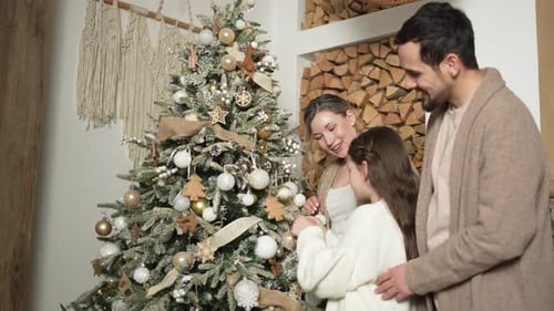 Family Decorating Christmas Tree with Ornaments and Ribbon