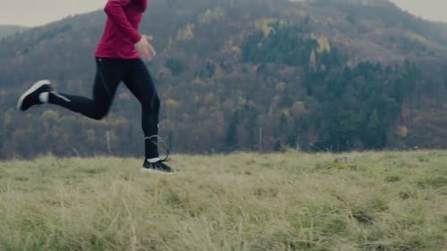 Young man running through autumn nature on a cloudy fall day in the forest