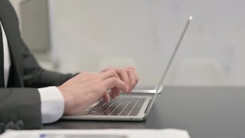 Side View of Businessman Typing on Laptop