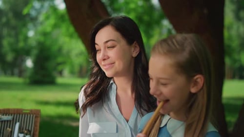Happy mother and daughter enjoying snack outdoors