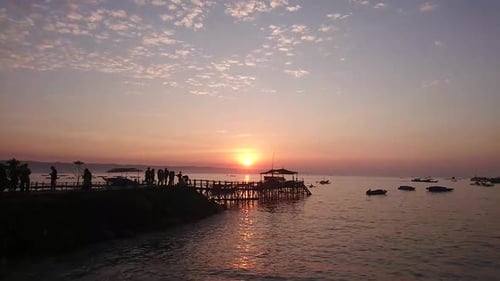 Time lapse shot the sea view scene at sunrise with the waves lapping on the beach, Fishing boats are