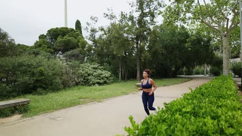 Young Sporty Woman Running in Slow Motion in a City Park
