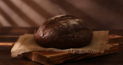 Fresh Dark Bread on Wooden Cutting Board Zooming