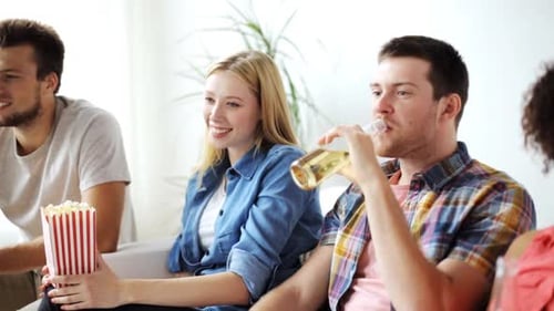Friends Relaxing on Sofa Drinking Beer and Eating Popcorn