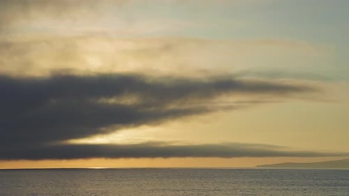 Black Sea and Beach Nearby Against a Sky with Clouds and a Dawn Sun
