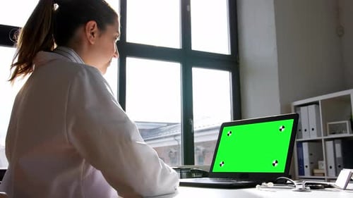 Woman doctor works at computer with chroma key