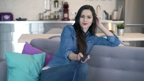 Woman Relaxing on Couch Using TV Remote