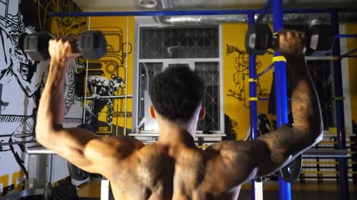 Sporty African Man with Tattoos Lifting Heavy Black Dumbbells at Sport Club Muscular Afro American