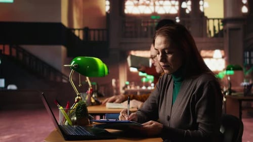 Femme mûre intellectuelle transcrivant un texte académique à partir d'un ordinateur portable