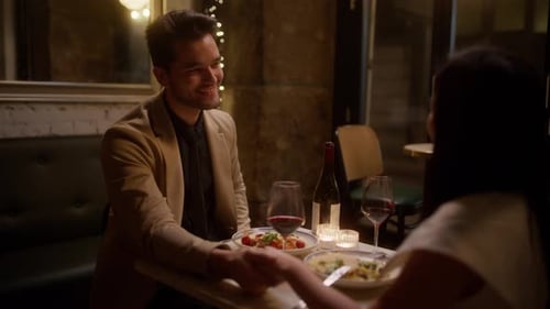 Guy touche doucement la main de son partenaire lors d'un dîner