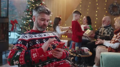 Man Using Phone With Family During Christmas Celebration