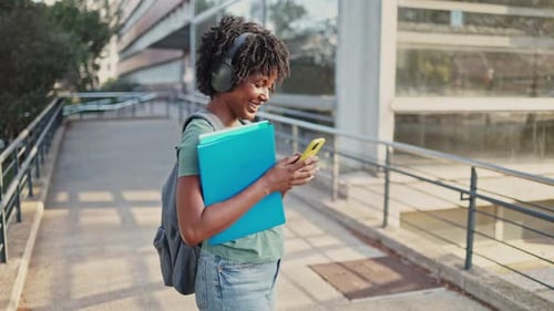 Young Woman Student Walking with Books and Cellphone