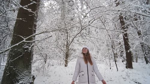 A Teenage Girl Walks Through the Snowy Forest