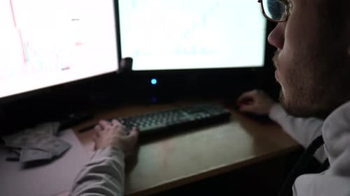 Male Trader Analyzing Commodities and Foreign Exchange Charts at Evening Young Financial Analyst