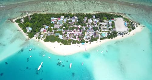 high altitude view of a resort in the Maldives with an atoll and the sea going from turquoise to dee