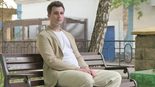 Young Adult Sits on Park Bench in Daytime