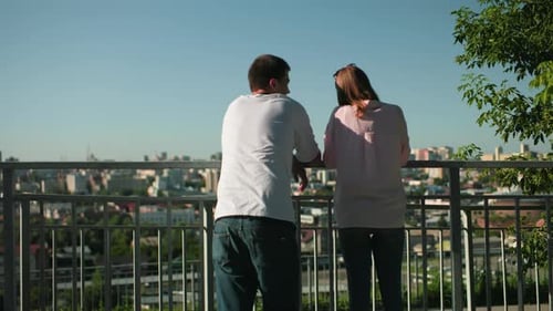 Couple Looking Over City From Elevated Viewpoint