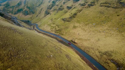 Car Driving on Curving Mountain Road with Green Hills Vehicle Traveling Along Scenic Route in Peak