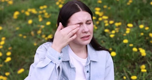 Woman suffering from seasonal allergy in park on spring day