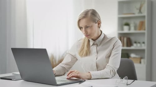 Woman Typing on Laptop at Bright Desk