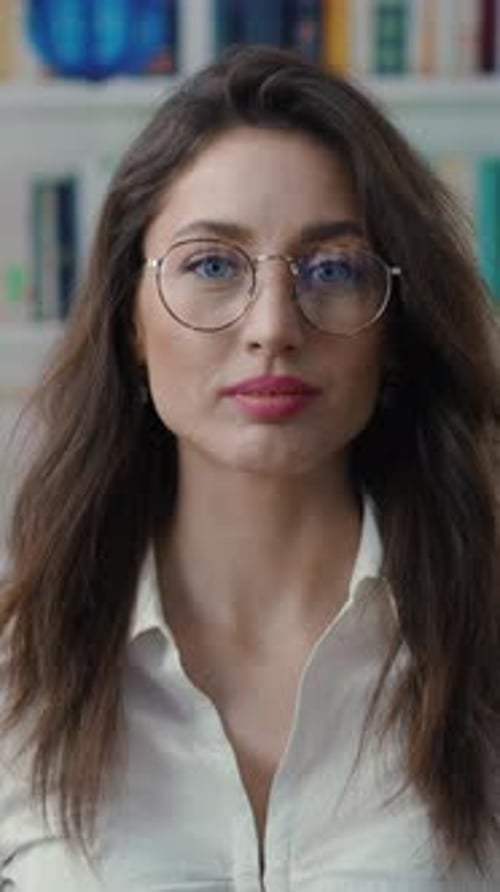 A Confident Young Woman Wearing Glasses Poses Against a Vibrant and Modern Background