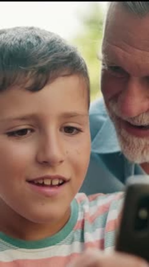 Smiling Boy Using Mobile Phone With Adult