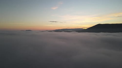Aerial View of Mountains Emerging from Clouds at Sunrise