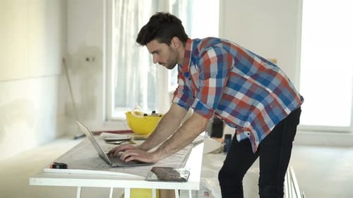 Young Man Using Laptop at Home Renovation Site