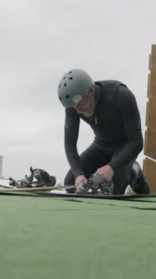 Person Adjusting Bindings on Board Outdoors
