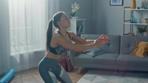 Close Up of a Fit Beautiful Female in an Athletic Top Doing Squat Exercises in Her Bright and Spaci