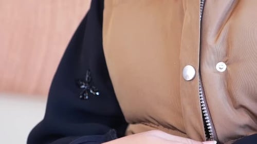 CloseUp of Person Zipping Brown Jacket Outdoors on a Cool Day