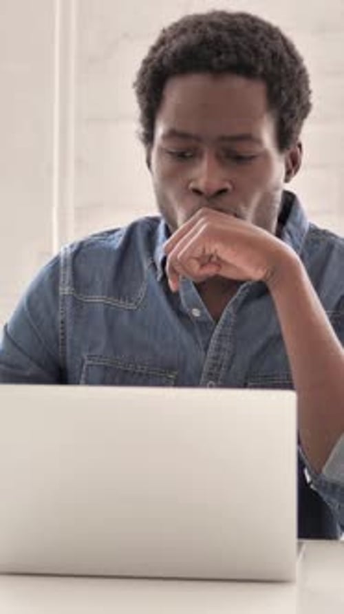 Pensive Man Working on Laptop at Desk Indoors