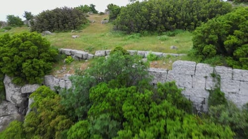 Anciennes ruines en pierre d'Assos cachées dans une végétation luxuriante à flanc de colline