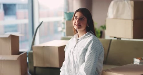 Smiling Woman in Apartment Surrounded by Moving Boxes