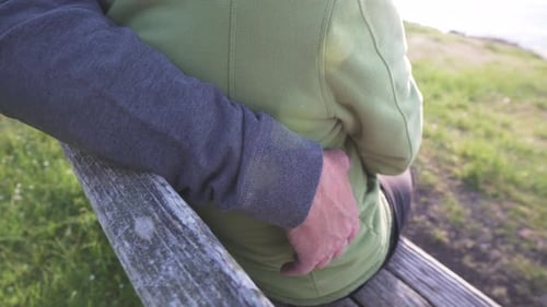 Adult romantic couple hug on coastline bench, back view
