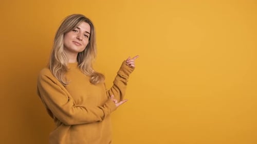 Woman Gesturing Towards Copy Space on Yellow Background