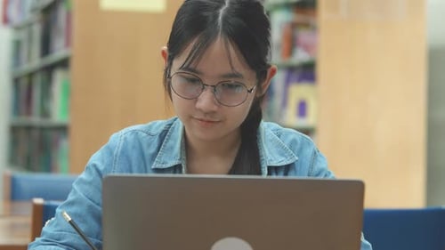 Young female student studying on her laptop computer in library