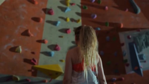 une femme se rend sur le mur d'escalade avec l'envie de gagner et commence à grimper