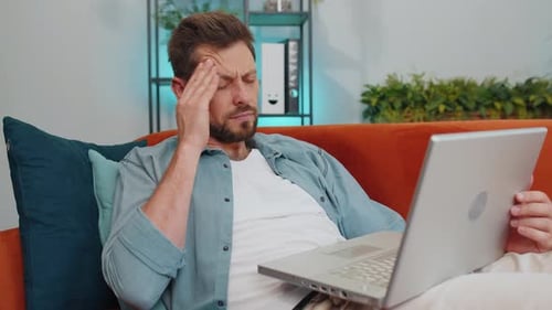 Frustrated Man Types on Laptop at Home