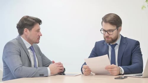 Businessmen Discussing Documents and Shaking Hands at Table