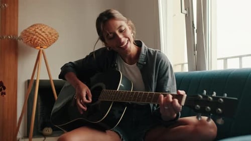 Woman Sings and Plays Guitar at Home