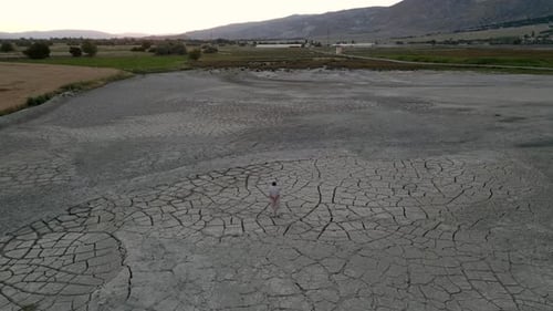 Lonely Figure in Cracked Earth at Sunset