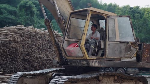 Young Asian Boy Operating the Controls of an Old Crawler Crane Moving Tree Trunks in Vietnam