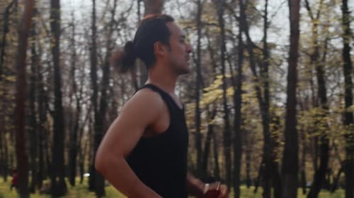 Young Asian Sportsman Running on an Alley in an Autumn City Park on a Sunny Day Side View Concept of