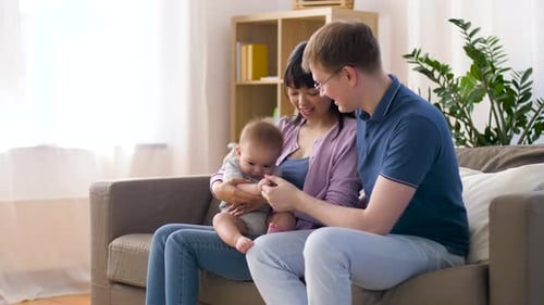 Parents playing with baby on sofa in living room