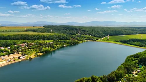 Scenic river landscape under blue sky. A tranquil river flows through lush green fields and hills