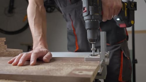 Man Using Drill on Wood in Bright Workshop