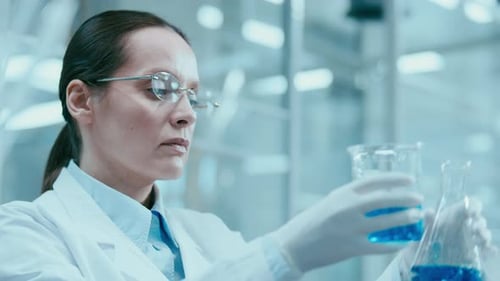 Woman Scientist Examining Blue Liquid in Beaker