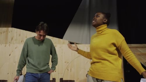 Joven pareja discutiendo en el escenario durante un ensayo teatral