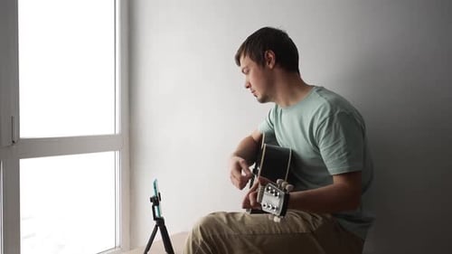 Young Adult Plays Guitar While Recording Himself